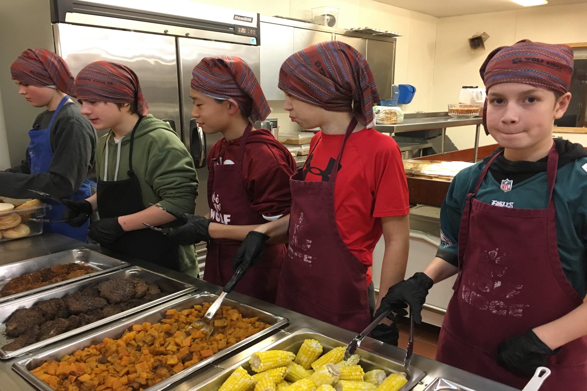 A group of boys serving food at a cafeteria